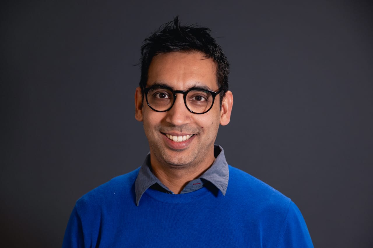 Mohit Gulati - Professional studio headshot in blue sweater with glasses